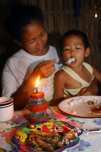 Image shows a mother and son eating meat and rice.